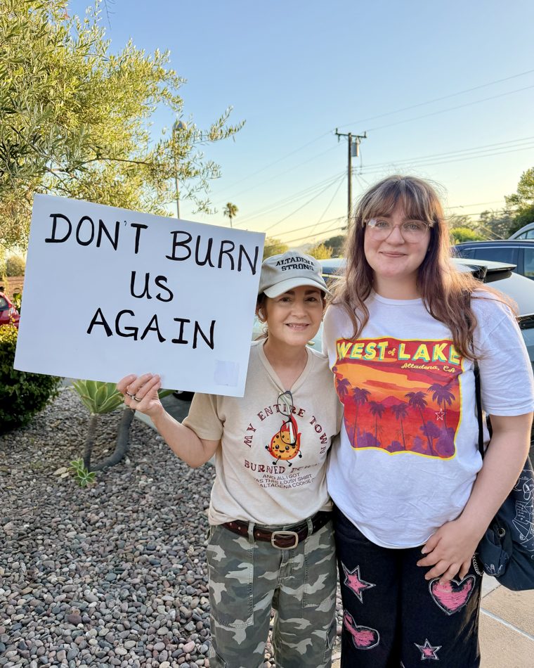 An Altadena resident holds a 'Don't Burn Us Again' sign at a community rally.