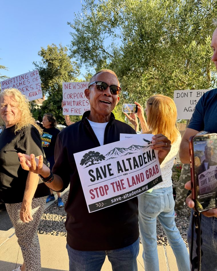 Altadena residents rally holding 'Save Altadena — Stop the Land Grab' signs.