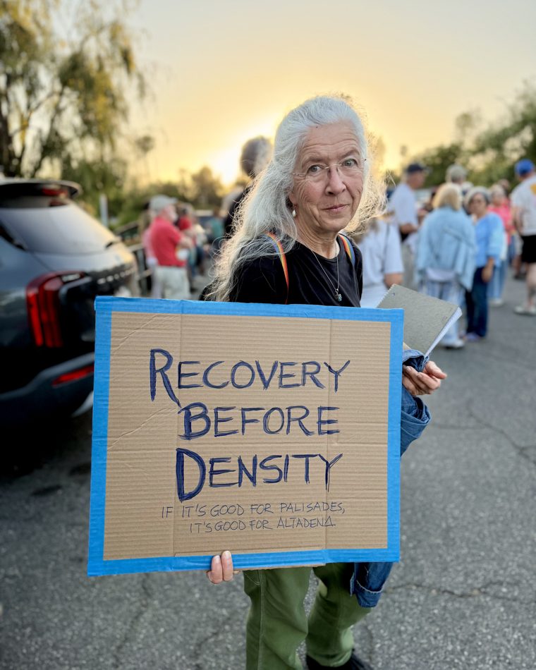 An Altadena resident holds a 'Recovery Before Density' sign at a community rally.